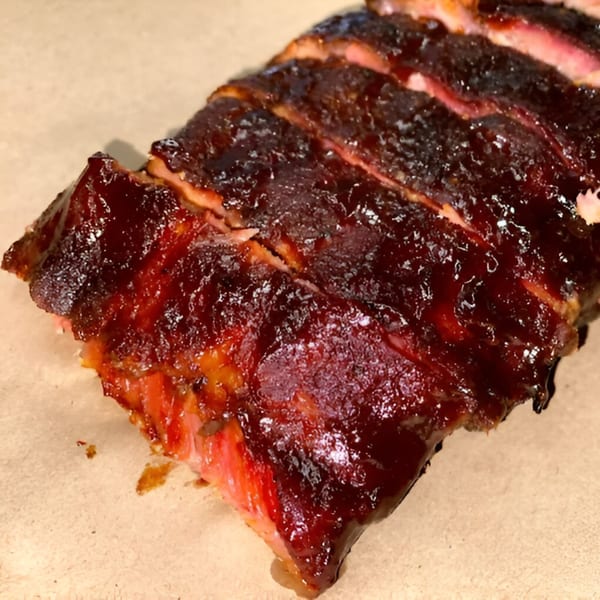 Close-up of Smoke BBQ's glistening, saucy ribs, sliced and ready to eat.